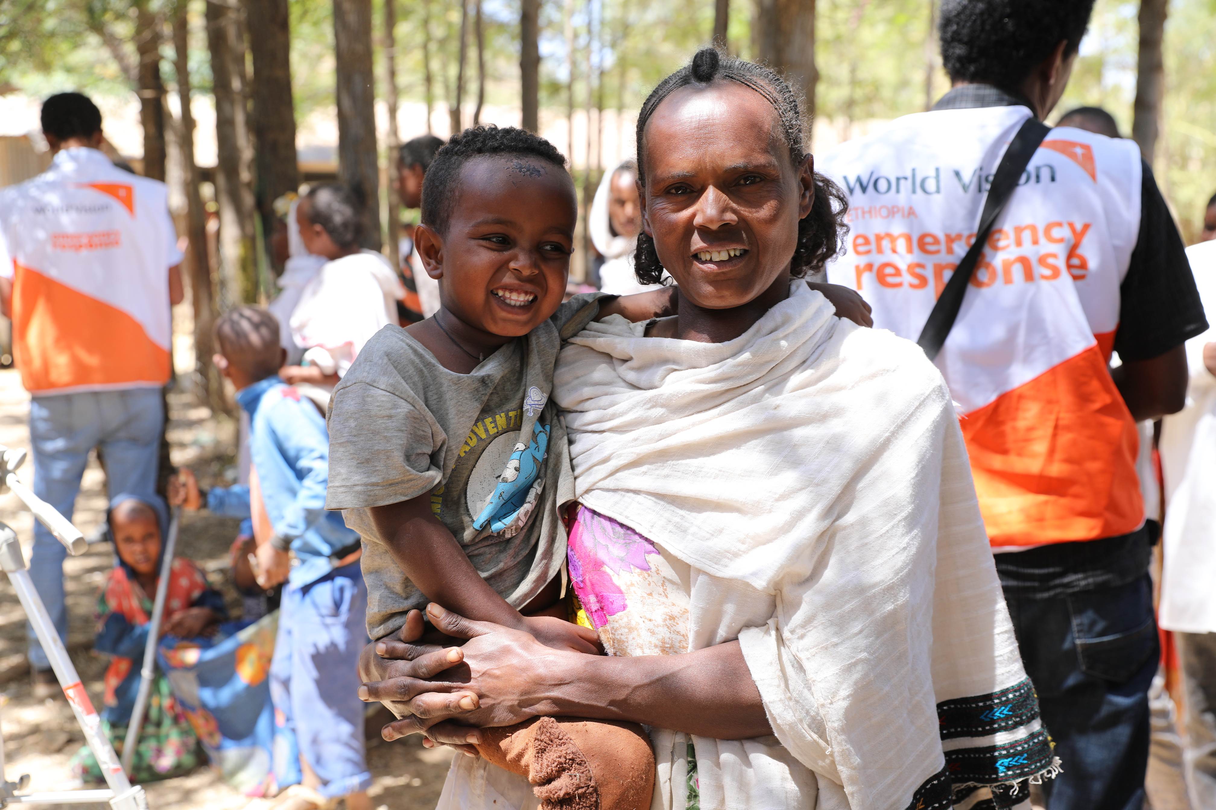 Una madre que carga a su hijo recibe apoyo de World Vision